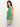 A person with long brown hair is wearing the Sanctuary Clothing open stitch shell sweater in palm and light blue jeans, standing sideways against a plain white background.