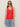 A woman in the Sanctuary Clothing mesh stitch shell sweater in cayenne, sunglasses, and light blue jeans stands against a beige background. She has long straight hair and a neutral expression.