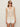 A woman with long, straight hair wears dark sunglasses, earrings, rings, and the Sanctuary Clothing mesh stitch shell sweater macrame”a sleeveless cream knit top”paired with white shorts against a plain background.