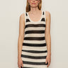 A woman in sunglasses and hoop earrings poses against a plain wall, wearing the mesh stitch shell sweater in black chalk stripe by Sanctuary Clothing.