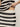 A person in a Sanctuary Clothing "crochet sweater skirt black chalk stripe" ensemble slightly lifts the top, revealing some midriff while wearing a gold ring. The background remains plain and neutral.