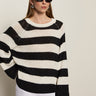 A woman in Sanctuary Clothing's textured raglan crew chalk black stripe 6 poses against a plain background, wearing dark sunglasses, white shorts, hoop earrings, and has straight light brown hair.