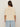 A person with long brown hair wears the Sanctuary Clothing tape yarn tee macrame in cream and light blue jeans, shown from the back against a beige background.
