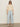A woman wears Sanctuary Clothing's tape yarn tee macrame, sunglasses, light blue wide-leg pants, beige woven shoes, and earrings against a plain light background.