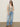 A woman wears the Sanctuary Clothing textured sweater vest macrame black stripe 3, light blue wide-leg jeans, and black sandals, standing against a plain wall with one hand in her pocket.