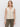 A woman with light brown hair models the Sanctuary Clothing textured sweater vest macrame�a sleeveless, cream knit design with buttons and two front pockets�paired with olive green pants against a white background.