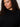 A woman with curly dark hair and natural makeup models the Sanctuary Clothing forever cashmere popover in black extended sizing, gazing confidently at the camera against a plain light background.