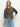 A woman with long blonde hair models the Sanctuary Clothing must have cardi french kitty, a leopard print sweater, styled with light blue jeans against a plain background, one hand in her pocket.