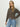 A woman with long blonde hair wears the Sanctuary Clothing must have cardi french kitty, standing against a plain light background with one hand on her hip, gazing confidently at the camera.