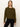 A woman with straight blonde hair wears Sanctuary Clothing's zip it sweater in dirty martini and black pants, standing against a plain off-white background, looking directly at the camera with a neutral expression.