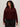 A woman with curly hair wears Sanctuary Clothing's boucle cardi in dark crimson (extended sizing) and black pants, standing against a plain, light-colored background.