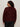 A person with curly dark hair, wearing Sanctuary Clothing's boucle cardi in dark crimson (extended sizing) and black pants, stands facing away from the camera against a light background.
