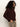 A woman with curly dark hair stands sideways against a plain background, wearing Sanctuary Clothing's boucle cardi in dark crimson and beige crushed velvet pants, with one hand in her pocket.