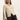 A woman with straight, long blonde hair wears the Sanctuary Clothing fitted raglan cardi in light oat with dark brown pants, standing against a plain light background.