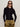 A woman with long brown hair wears black oval sunglasses, shiny gold pants, and the Sanctuary Clothing button down variegated cardi black, standing against a plain light background with her hands in her pockets.