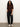 A woman with long curly hair wears the Sanctuary Clothing perfect sweater tee in chicory, paired with black cargo pants and white sneakers. She stands against a plain light-colored wall with her hands in her pockets.