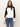 A woman with long brown hair wears the Sanctuary Clothing downtown mock neck sweater in black chalk and blue jeans, standing against a plain light background and looking directly at the camera.
