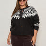 A woman wearing Sanctuary Clothing’s fairisle crewneck cardi ink multi (extended sizing), featuring white and black Fair Isle patterns, stands confidently against a light background, sunglasses on and hands by her sides.