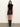A woman with long brown hair and a neutral expression wears the Sanctuary Clothing city sweater shell in black against a plain light background, paired with a leather mini skirt and knee-high black boots.