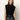 A woman with wavy brown hair wears the Sanctuary Clothing city sweater shell in black, paired with high-waisted black leather pants, standing against a light background and looking at the camera with a neutral expression.