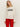 A person with straight blonde hair wears Sanctuary Clothing„¢s 24/7 Popover Chalk with œJ„¢ADORE� in bold black letters, paired with bright red pants, standing against a light background.