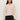 A woman with long dark hair wears the Sanctuary Clothing dreamy v neck sweater in heather rose and black pants, standing against a light background with a neutral expression, facing forward.