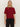 A woman with straight blonde hair wears the Sanctuary Clothing short sleeve shine sweater tee in cherry lacquer shine, featuring red and black horizontal stripes with subtle sparkle, paired with black pants against a light background.