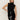 A woman with long blonde hair models the Sanctuary Clothing scarf sweater shell in black, posing with one hand on her hip against a plain light background.