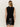 A woman with straight blonde hair models the Sanctuary Clothing scarf sweater shell in black, featuring scarf-like back details. She pairs it with a shiny black leather mini skirt, standing against a neutral background.