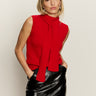 A woman with straight blonde hair models Sanctuary Clothing's cherry lacquer scarf sweater shell, a sleeveless red top with a long scarf detail, paired with a shiny black leather skirt against a plain background.