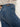 A person wears Sanctuary Clothing soleil 90s straight jeans in indigo medium with a light shirt and brown heeled ankle boots, standing on a gray floor against a plain light background. The image is cropped from the shoulders down.