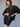 A woman poses confidently in a black varsity jacket with leather sleeves and the camden skirt black by Sanctuary Clothing against a plain background.
