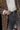 A person wearing a leopard print coat, a white button-up shirt, black belt, and gray jeans. The person is holding the lapel of the coat with one hand, focusing on their midsection and outfit details.