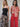 Two women stand side by side; one wears Sanctuary Clothing's "meet me at sea midi dress" in black mirage, while the other sports a red and beige patterned collared shirt with red wide-leg pants. Both have loose waves and minimal jewelry.