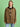 A woman stands against a green background wearing the save our planet jacket timber by Sanctuary Clothing x PEANUTS 75th Anniversary, featuring large front pockets, Peanuts embroidery, over a black-and-white striped shirt and light blue jeans.