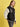A person models the Sanctuary Clothing x PEANUTS 75th Anniversary "75 varsity jacket black white" against a yellow background, glancing to the side with one hand in their pocket.