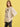 Woman wearing a beige sweatshirt with a graphic design on a yellow background