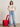 A woman stands indoors wearing the doctor is in tee collagen from Sanctuary Clothing x PEANUTS 75th Anniversary, paired with light blue wide-leg jeans and red shoes, posing beside a red sculptural chair against a plain wall.
