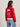 A woman wears the Sanctuary Clothing x PEANUTS 75th Anniversary "joe cool zip up sweater cherry lacquer," featuring a Snoopy graphic on the back, with light blue jeans. She faces away, looking to the side.