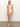 A person is wearing the Sanctuary Clothing charming floral V Wire Mio in white, featuring a pink, green, and white floral pattern. They're standing barefoot on a gray floor against a plain background.
