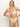 A person with long, light-blonde hair confidently poses against a plain background wearing the Sanctuary Clothing's charming floral v wire bandeau white bikini, featuring large pink, green, and orange flowers with a straight neckline and medium straps.
