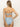 A person with long blonde hair is wearing the Refresh Rib Bandeau Blue Chateau set by Sanctuary Clothing, featuring a light blue, ribbed bandeau top that ties at the back and a high-waisted bottom. They stand against a plain, light-colored background.