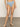 A person wearing Sanctuary Clothing's refresh rib high leg high rise blue chateau stands on a concrete floor, facing the camera against a plain, neutral-toned background.