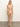 A person stands against a plain background wearing the Sanctuary Clothing Stay Connected high leg hipster bikini bottom in Cherry Blossom. They have long hair, are barefoot, and exude a relaxed and confident pose.