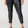 A person is wearing the Runway Legging Black Inclusive Collection from Sanctuary Clothing paired with black open-toe sandals featuring a cork heel. The individual is also wearing a green camouflage top. The background is plain and light-colored.