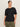 A woman with dark hair tied back wears the Sanctuary Clothing shirred waist dolman tee in black (extended sizing), paired with olive green cargo pants, standing against a plain light background and looking confidently at the camera.