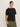 A woman with dark hair tied back wears Sanctuary Clothing's shirred waist dolman tee in black (extended sizing) and olive green cargo pants, standing against a plain light background and looking confidently at the camera.