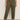 A person stands against a plain light background wearing Sanctuary Clothing's boyfriend utility pant kalamata extended sizing with large front pockets, paired with a black t-shirt and white sneakers featuring black accents. Their arms are relaxed by their sides.