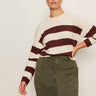 A woman models the Sanctuary Clothing 24/7 Popover Chicory Light Oat (extended sizing) sweater, featuring cream and dark red stripes, paired with olive green high-waisted cargo pants against a plain light background.