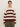 A person with dark hair tied back is wearing the Sanctuary Clothing 24/7 Popover Chicory Light Oat sweater, featuring cream and maroon stripes, paired with olive green pants against a plain light background.